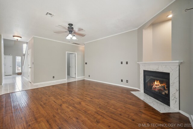unfurnished living room with a premium fireplace, a ceiling fan, visible vents, and baseboards