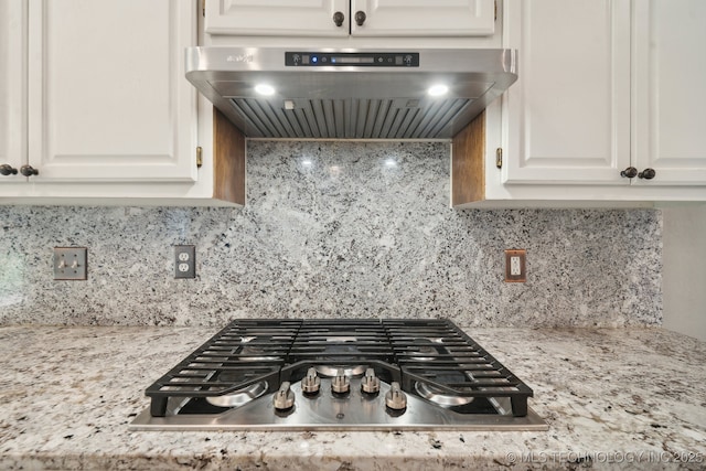 kitchen featuring stainless steel gas stovetop, white cabinets, tasteful backsplash, and extractor fan