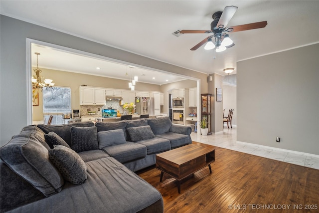 living room featuring ceiling fan with notable chandelier, light hardwood / wood-style flooring, and ornamental molding