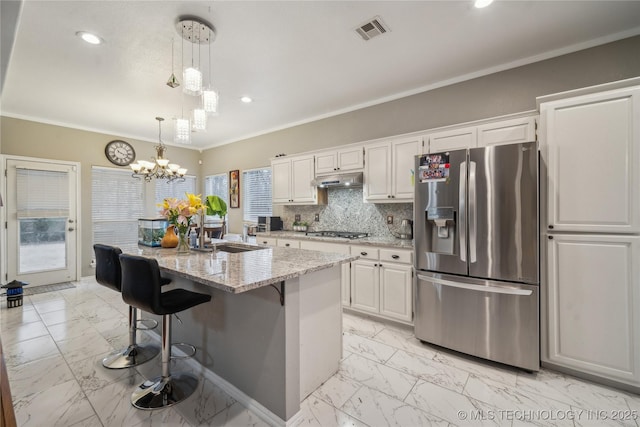 kitchen with sink, appliances with stainless steel finishes, white cabinetry, light stone countertops, and an island with sink