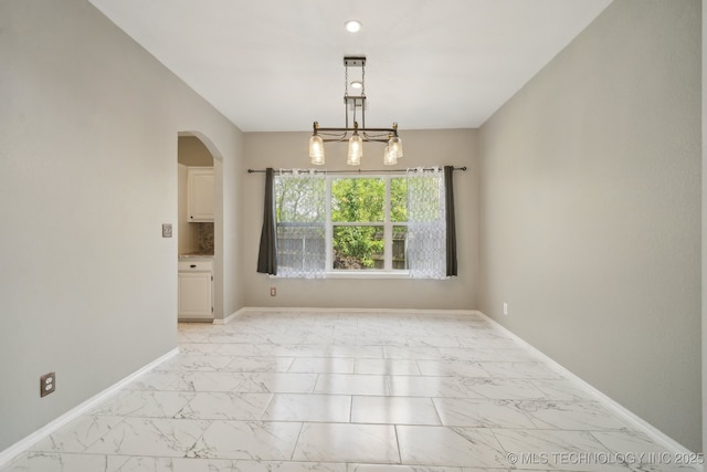 spare room with arched walkways, baseboards, and marble finish floor