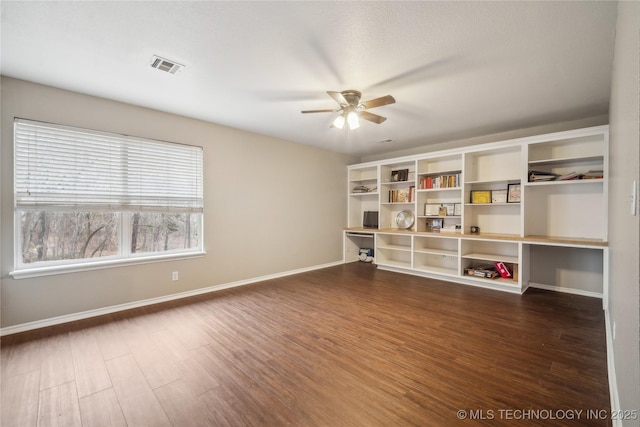 unfurnished room with dark wood-type flooring, built in desk, and ceiling fan