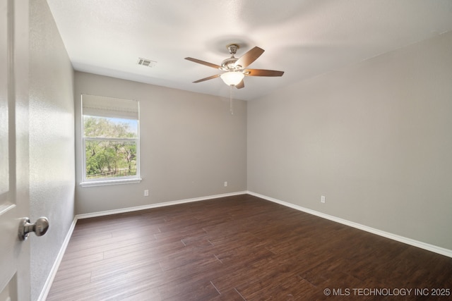 empty room featuring visible vents, a ceiling fan, dark wood finished floors, and baseboards