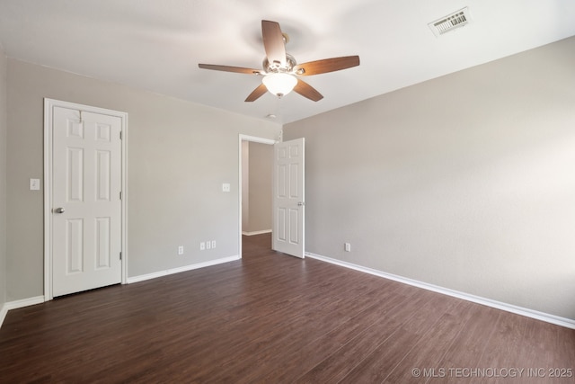unfurnished bedroom featuring dark wood-style flooring, baseboards, visible vents, and ceiling fan
