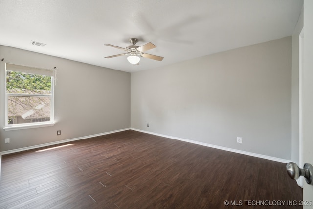unfurnished room with dark wood-style flooring, ceiling fan, visible vents, and baseboards