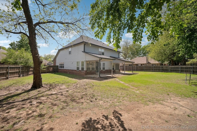 rear view of property featuring a yard, a fenced backyard, and a patio area