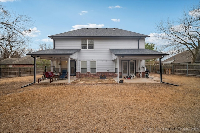 rear view of house featuring a fenced backyard, a patio area, and roof with shingles