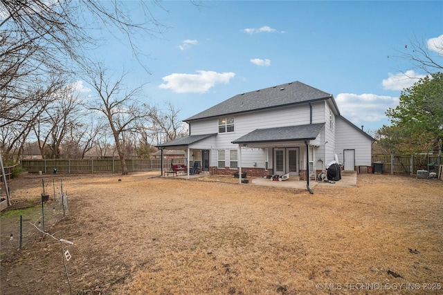 rear view of property with a fenced backyard, a patio area, roof with shingles, and french doors