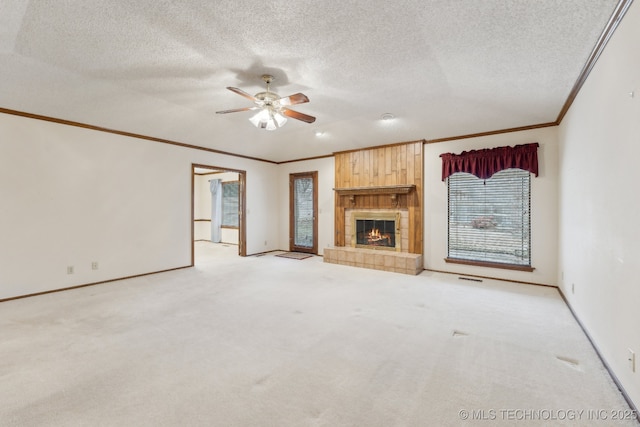 unfurnished living room with crown molding, light colored carpet, a tiled fireplace, and a textured ceiling