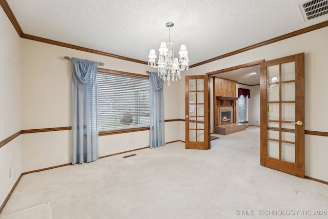 spare room featuring crown molding, french doors, a textured ceiling, and carpet flooring