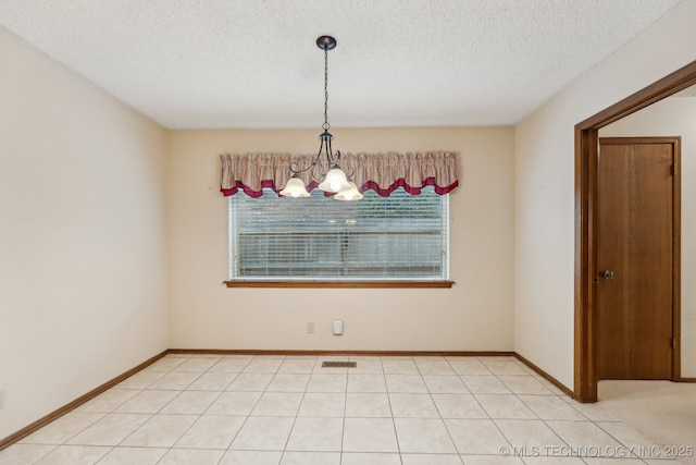 unfurnished room with a notable chandelier, a textured ceiling, and a healthy amount of sunlight