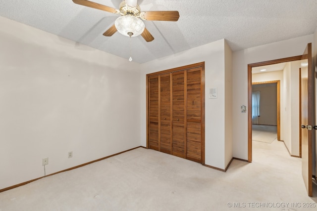 unfurnished bedroom with ceiling fan, light colored carpet, a closet, and a textured ceiling