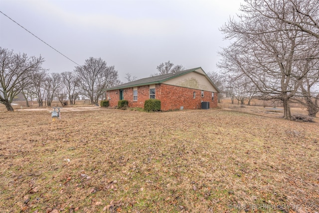 view of side of home featuring cooling unit and a lawn