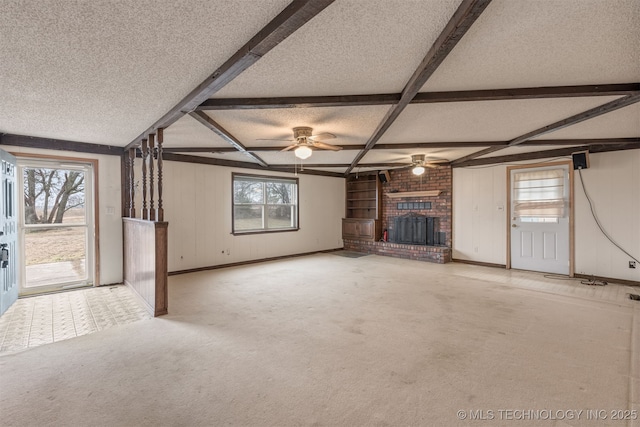 unfurnished living room with beam ceiling, a brick fireplace, a wealth of natural light, and a textured ceiling