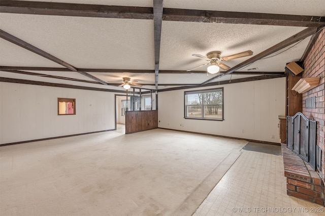 unfurnished living room featuring beamed ceiling, ceiling fan, a fireplace, and a textured ceiling