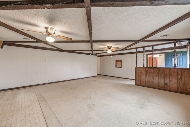 spare room with beamed ceiling, ceiling fan, a textured ceiling, and wood walls