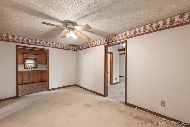 empty room featuring light carpet, sink, a textured ceiling, and ceiling fan