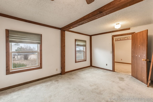 empty room with beamed ceiling, light colored carpet, and a textured ceiling