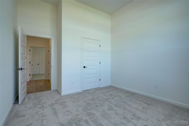 unfurnished bedroom featuring a towering ceiling and light colored carpet