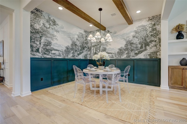 dining room with built in shelves, light hardwood / wood-style floors, a chandelier, and beamed ceiling