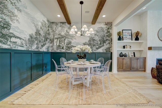 dining space with light wood-type flooring, a chandelier, built in features, and beam ceiling