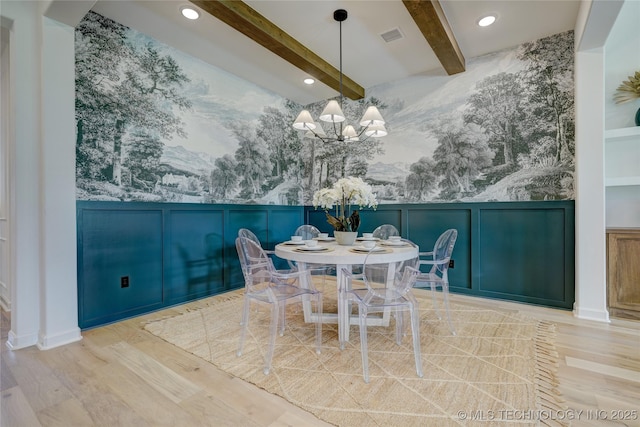 dining space featuring beam ceiling, light hardwood / wood-style floors, and a chandelier