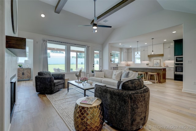 living room featuring lofted ceiling with beams, ceiling fan, and light wood-type flooring