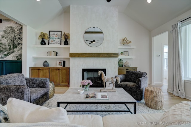 living room with vaulted ceiling, light hardwood / wood-style floors, a large fireplace, and plenty of natural light