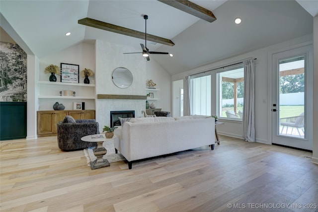 living room featuring high vaulted ceiling, a fireplace, beamed ceiling, ceiling fan, and light hardwood / wood-style floors