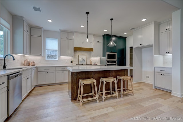 kitchen featuring stainless steel appliances, a center island, sink, and white cabinets