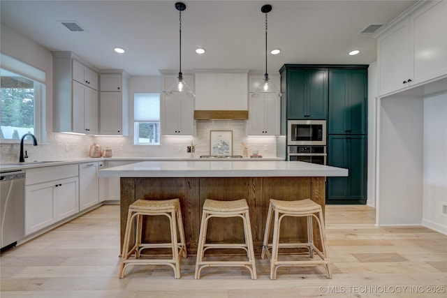 kitchen featuring stainless steel appliances, sink, a kitchen island, and white cabinets