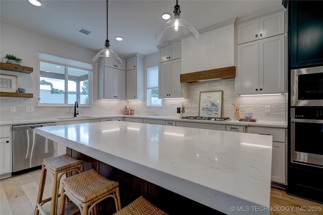 kitchen with white cabinetry, sink, stainless steel appliances, and a center island