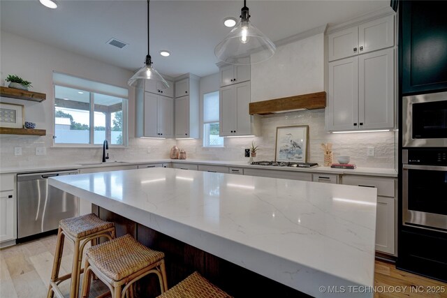 kitchen featuring white cabinetry, sink, a kitchen island, and appliances with stainless steel finishes