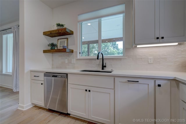 kitchen featuring sink, dishwasher, white cabinets, decorative backsplash, and light wood-type flooring