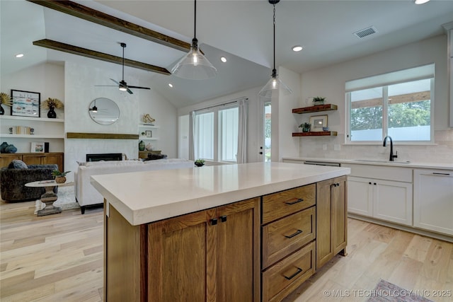 kitchen featuring a kitchen island, decorative light fixtures, sink, vaulted ceiling with beams, and white cabinets