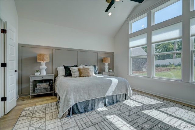 bedroom featuring ceiling fan, high vaulted ceiling, and light wood-type flooring