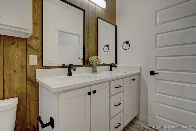 bathroom with wooden walls, vanity, and toilet