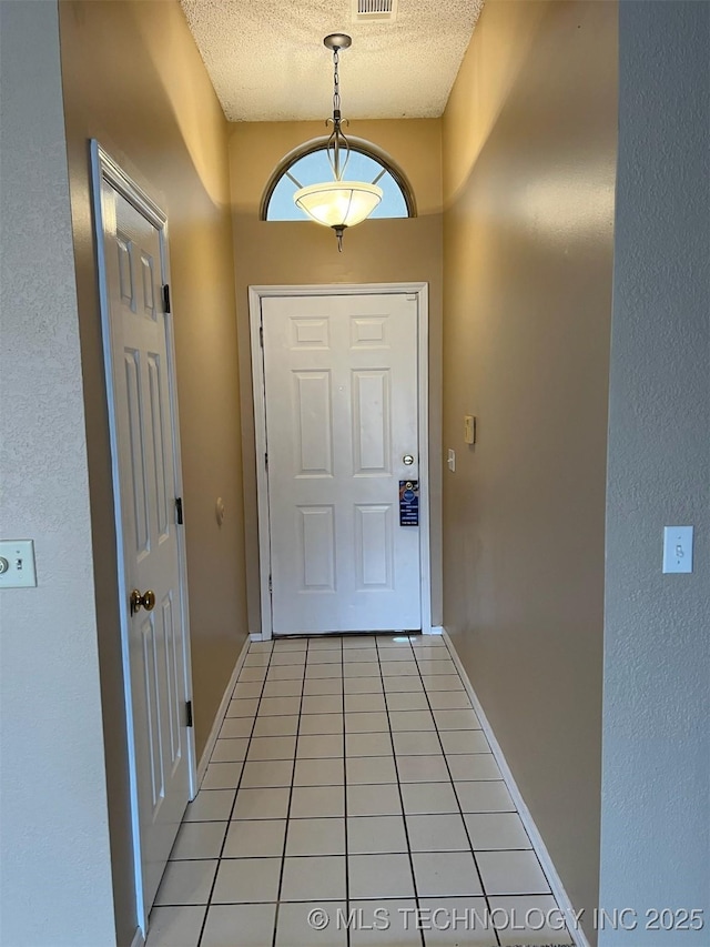 entryway with a textured ceiling and light tile patterned floors