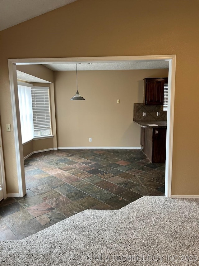 interior space with vaulted ceiling and dark carpet