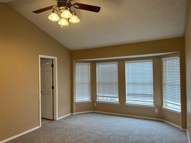 carpeted spare room featuring ceiling fan, vaulted ceiling, and a textured ceiling