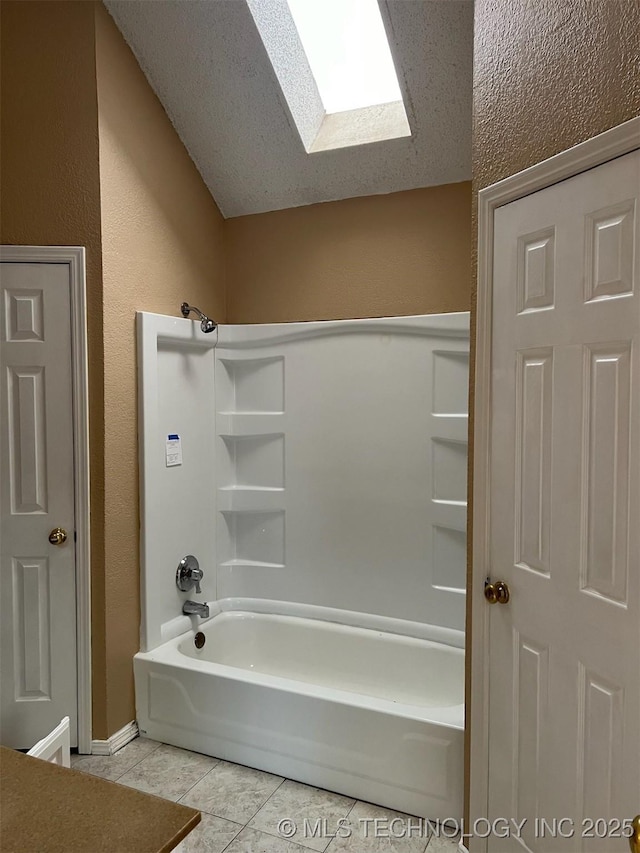 bathroom with tub / shower combination, a skylight, tile patterned floors, and a textured ceiling