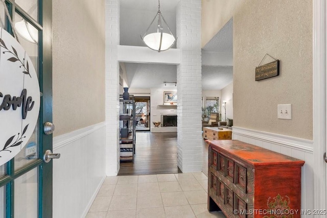 tiled foyer entrance featuring decorative columns and a textured ceiling