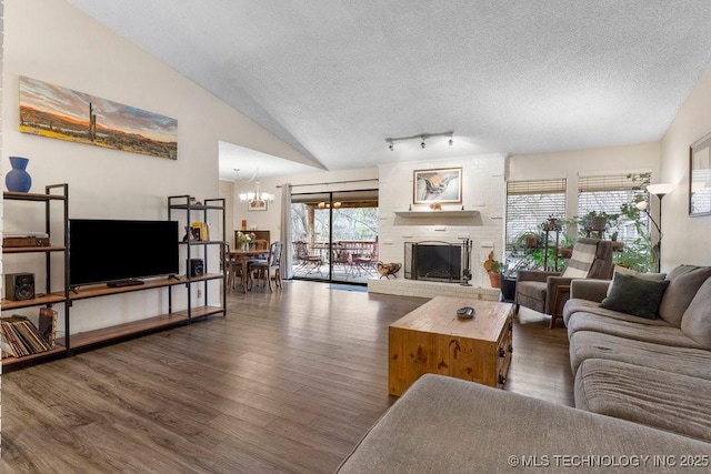 living room featuring dark wood-type flooring, a large fireplace, lofted ceiling, and a textured ceiling