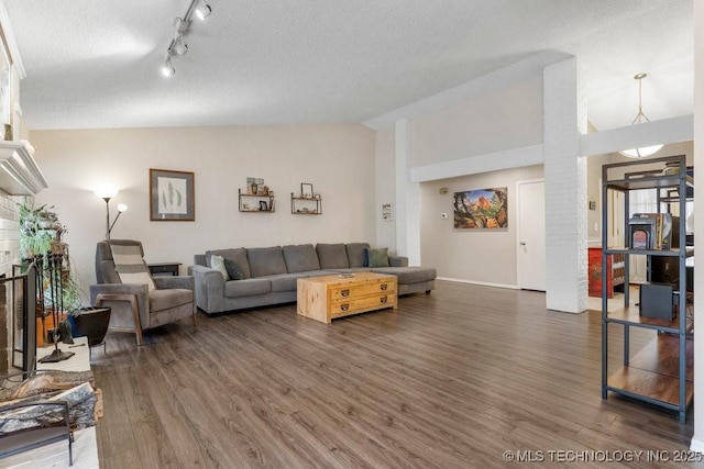 living room featuring a brick fireplace, dark wood-type flooring, vaulted ceiling, and a textured ceiling