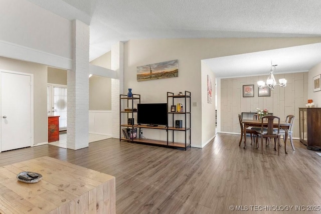 living room with lofted ceiling, hardwood / wood-style floors, a chandelier, and a textured ceiling