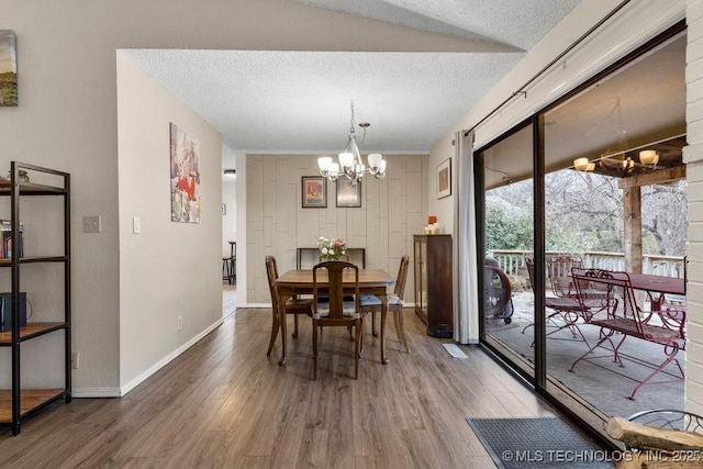 dining area with a chandelier, hardwood / wood-style floors, and a textured ceiling