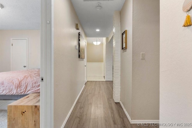 corridor featuring wood-type flooring and a textured ceiling