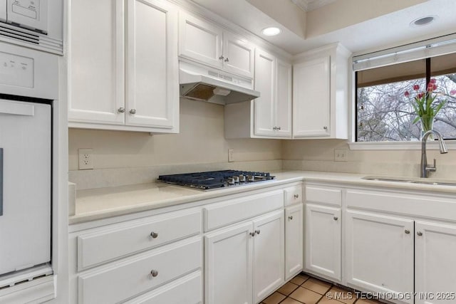 kitchen featuring white cabinetry, stainless steel gas stovetop, sink, and light tile patterned floors