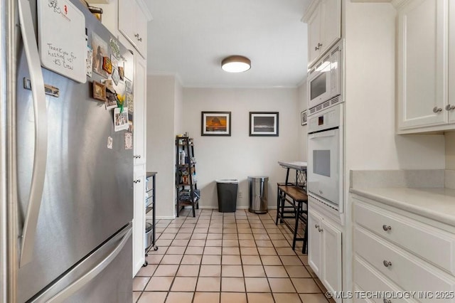 kitchen with crown molding, light tile patterned floors, white cabinets, and white appliances