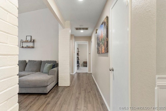 hall with hardwood / wood-style flooring and a textured ceiling